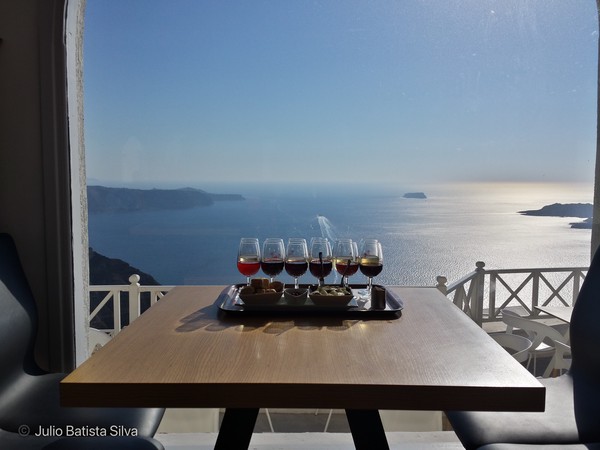 A tray of wine glasses and snacks on a table overlooking the sea.